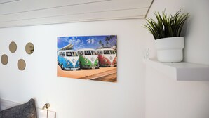 En vägg med en målning av en VW-buss, en växt och runda väggdekorationer.
