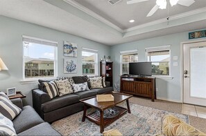 Relax in this inviting living room with a sofa, coffee table, and television, surrounded by natural light and a decorative piece.