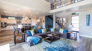 A spacious living area with a large sectional sofa, a coffee table, and a staircase leading to an upper level.