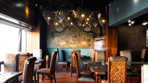 Een restaurantinterieur met gestreept meubilair, een grote decoratieve wand en hangende lampen.