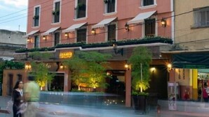 Een meerlaags hotel met een rode gevel, veel ramen en buitenruimtes met beplanting.