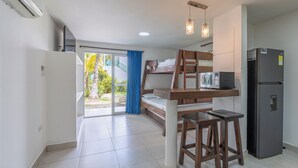 A compact room with a bunk bed, a kitchenette with a refrigerator and microwave, and a sliding glass door leading to an outdoor area. - Cabañas Aqua Blue Coveñas (Coveñas)