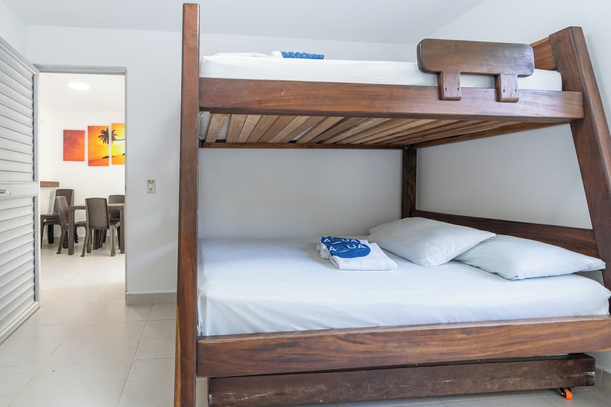 A bunk bed with white bedding and a towel with a logo.