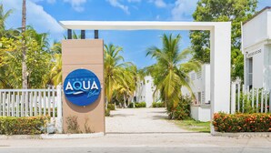 A gated entrance with a sign reading 'AQUA Blue' and a white building with a flat roof. - Cabañas Aqua Blue Coveñas (Coveñas)