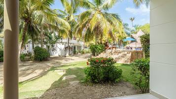 Un patio con palmeras, una estructura de techo de paja y una zona de piscina.