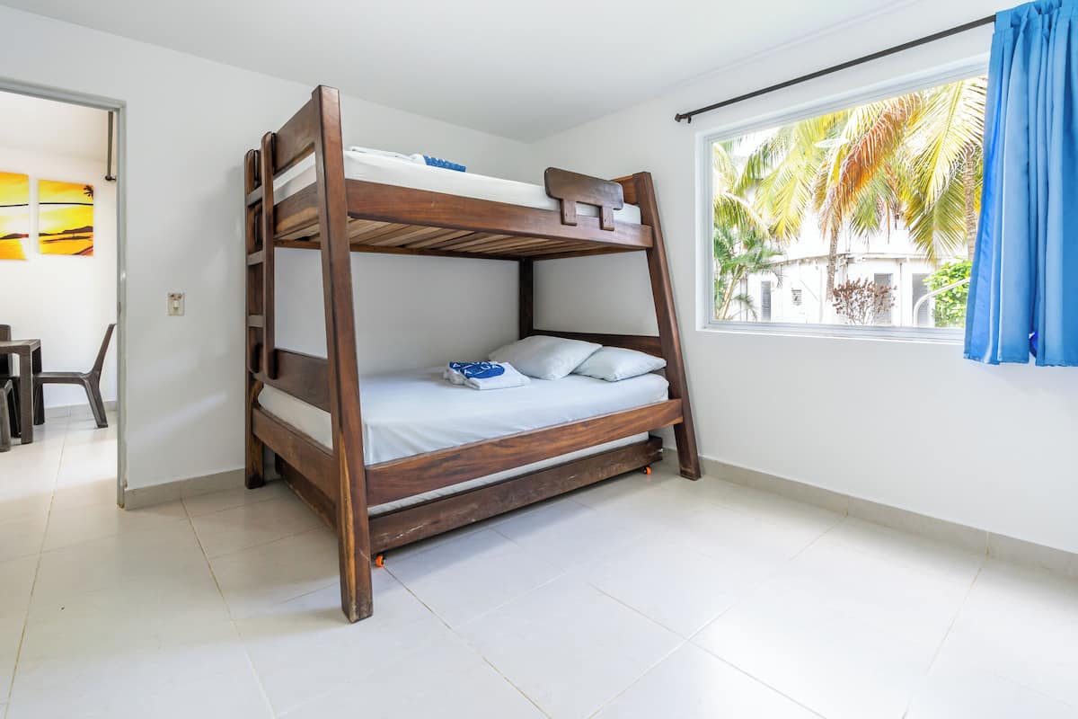 A bunk bed in a room with a window, white walls, and a tiled floor.