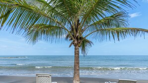 A beach with a palm tree and two white lounge chairs facing the ocean. - Cabañas Aqua Blue Coveñas (Coveñas)