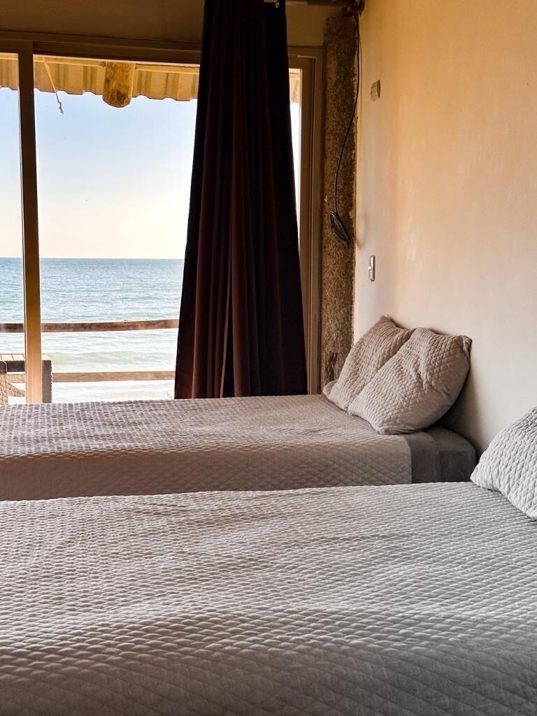 Un dormitorio con cama, ventana con cortinas y vista al mar.