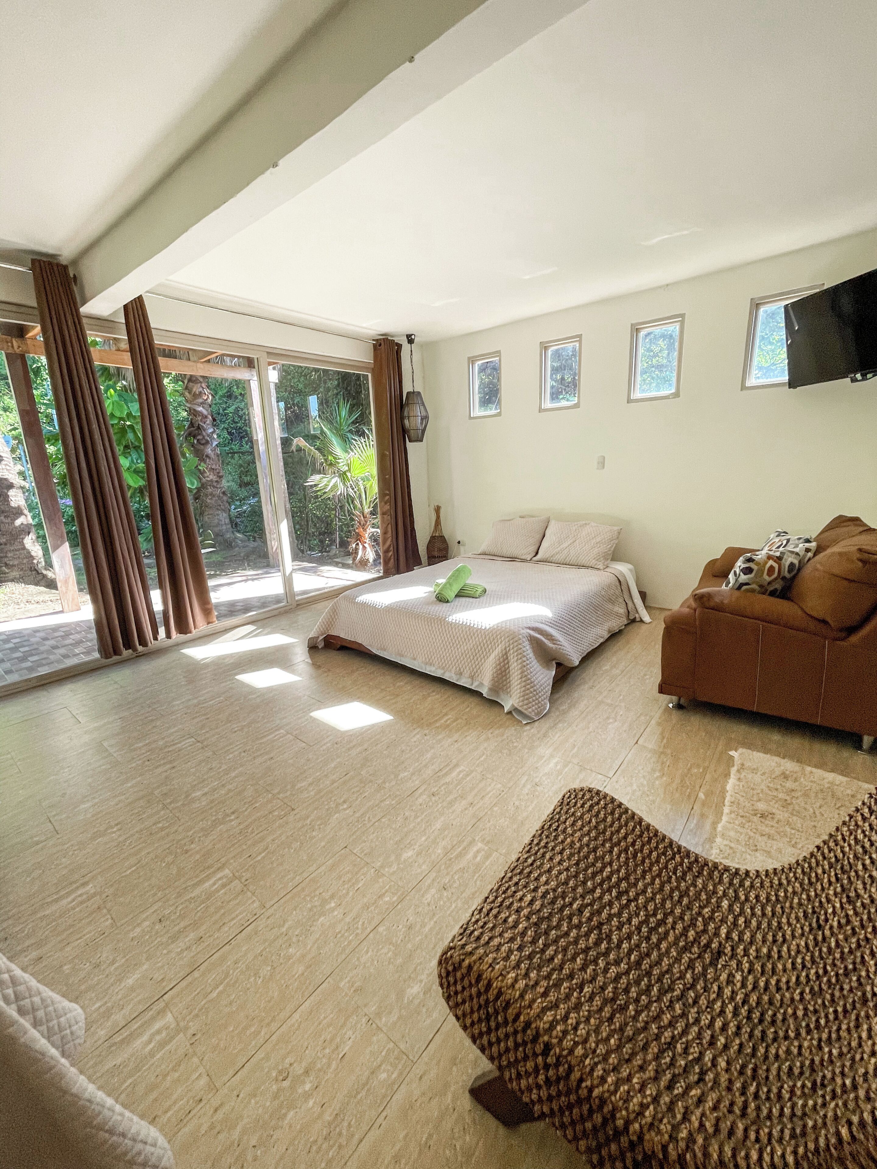 A spacious room with a bed, a sofa, and a TV.
