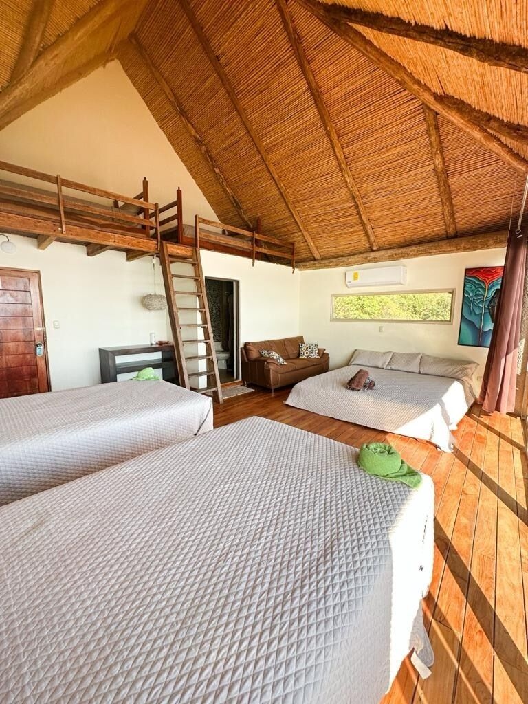 Ein Zimmer mit zwei Betten, einer Leiter, einem Sofa und einem Gemälde an der Wand.
