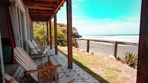 Un espace extérieur abrité, avec des chaises en bois et une vue sur la plage.