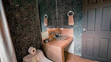 A bathroom with a toilet, sink, and mirror.