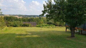 A grassy outdoor area with a tree and a building in the background. - Quiet country house (Triguères)