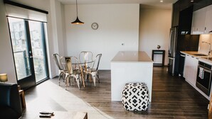 Une cuisine moderne avec un plancher en bois foncé, un îlot central et un coin repas comprenant des chaises et une table.