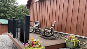 A wooden deck with two rocking chairs and a planter with flowers.