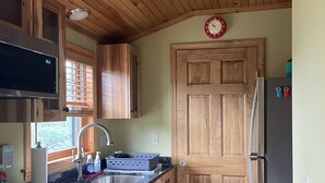 A kitchen with wooden cabinets, a stainless steel refrigerator, a microwave, and a sink.