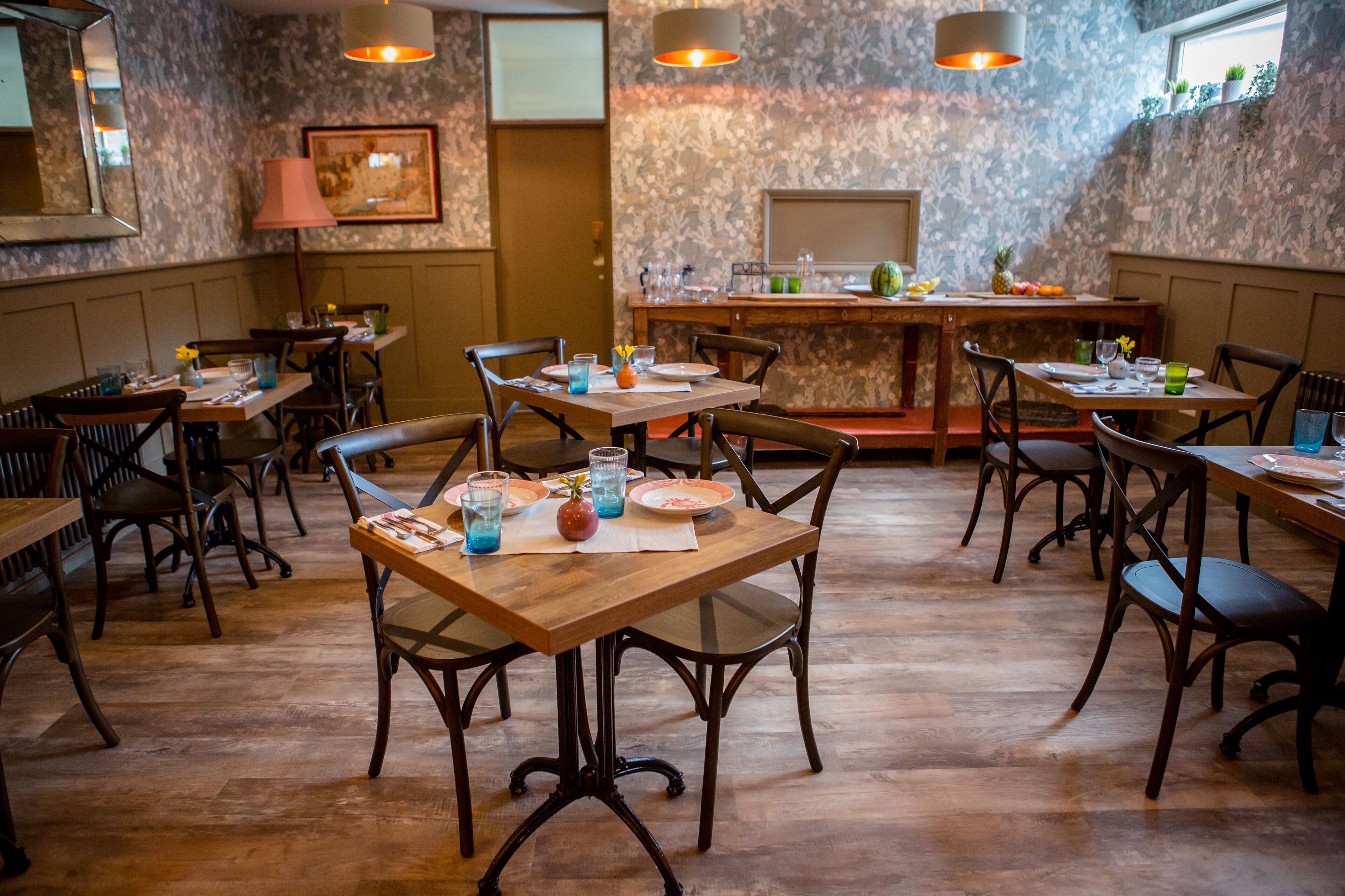 Een restaurant met houten tafels en stoelen, een bar en een wand met een patroon.