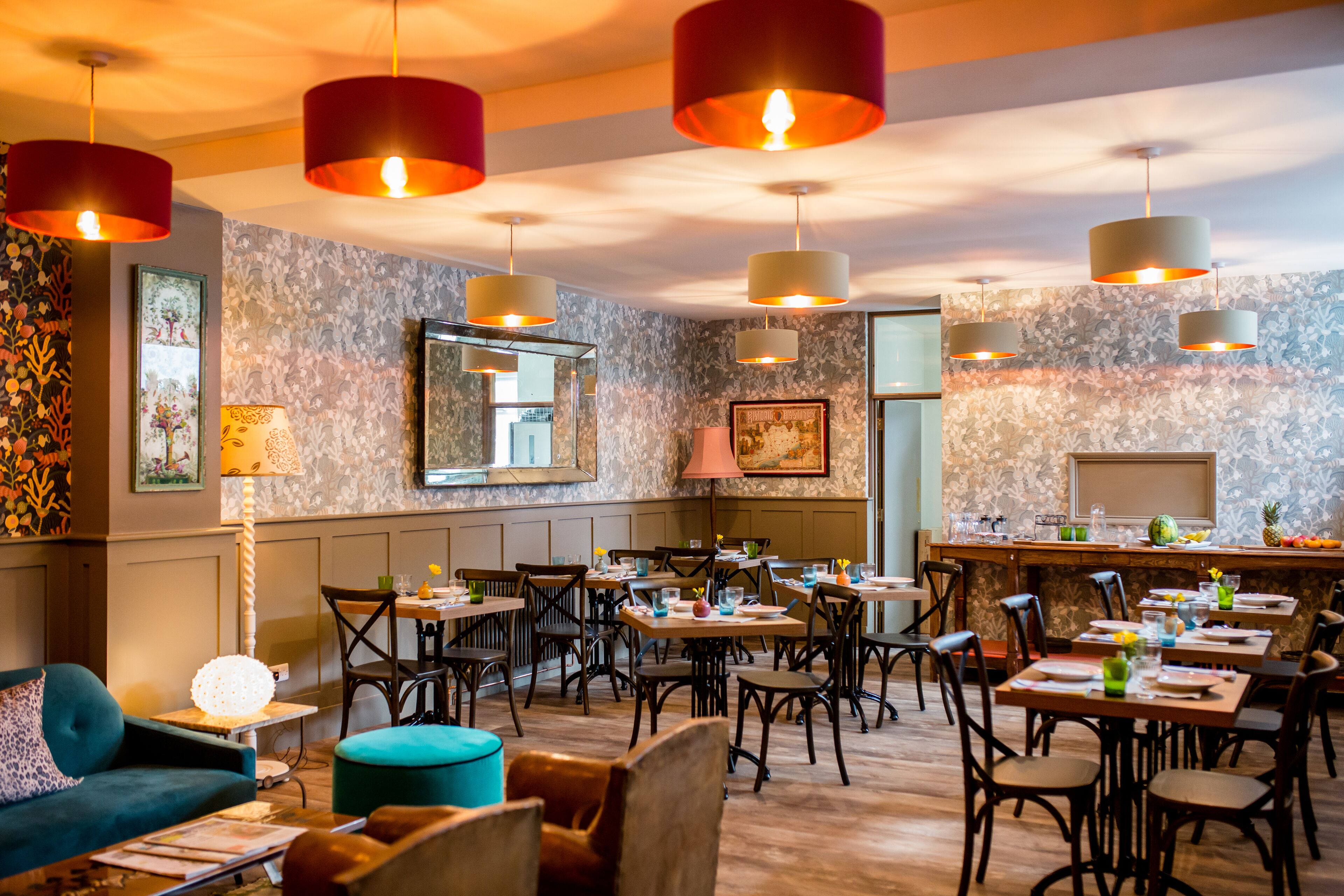 A restaurant with multiple tables and chairs, a bar area, and a seating area with a sofa and ottoman.