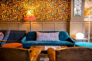 A cozy living area with a teal sofa, patterned cushions, and a coffee table with magazines.