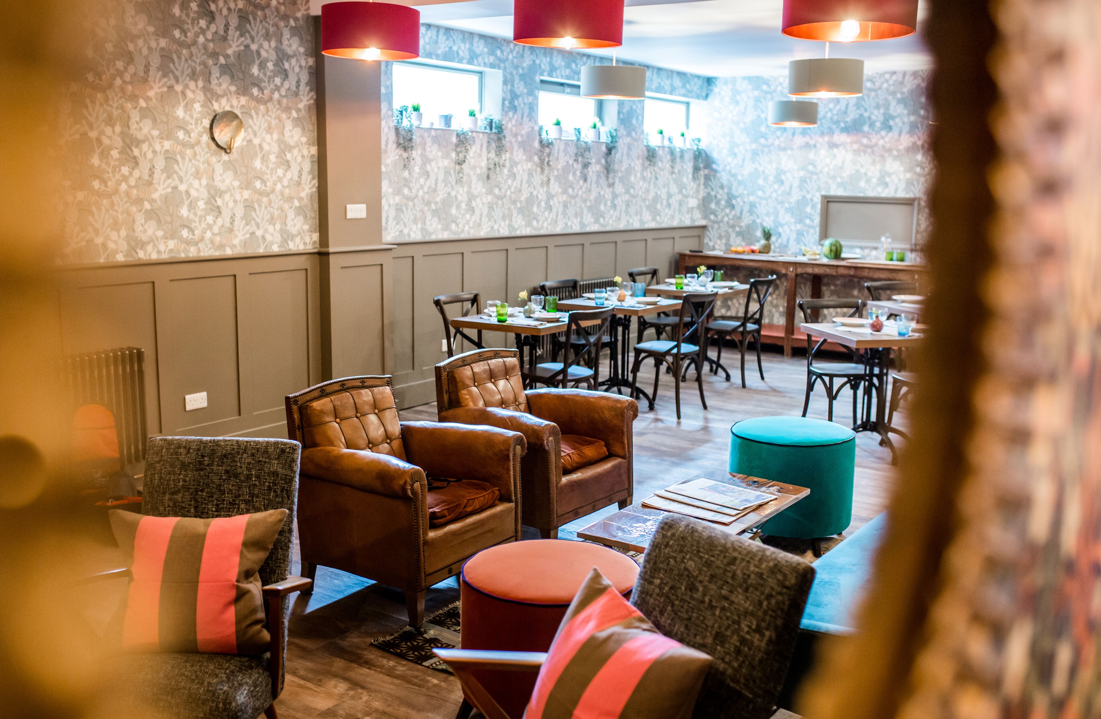 Ein Restaurantinneres mit Ledersesseln, Holztischen und Pendelleuchten.
