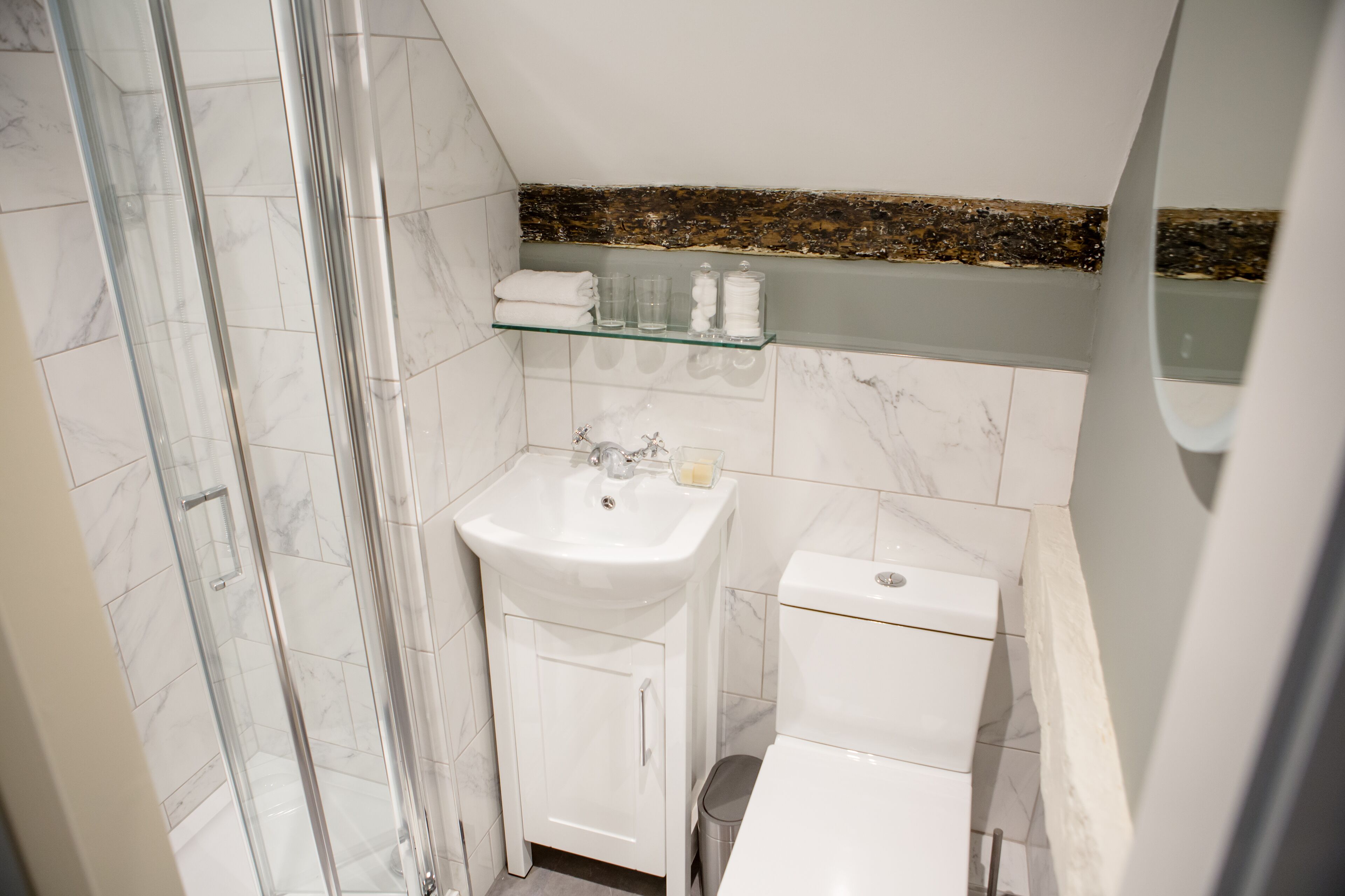 Un baño con cabina de ducha de vidrio, un lavamanos blanco y un inodoro.