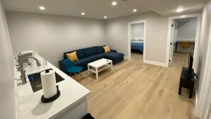 Een moderne woonkamer met een bank, salontafel, en een keukenhoek met een spoelbak en aanrecht.