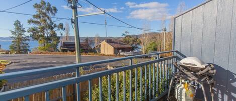 A balcony with a motorcycle, a wooden fence, and a view of a road and buildings.