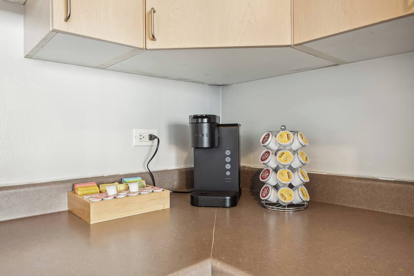 Une cuisine équipée d’une machine à café, d’un porte-tasse et d’un paquet de capsules de café.