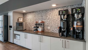 Een moderne keuken met ingebouwde koffieautomaten, een magnetron en een koelkast.