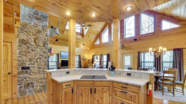 A spacious kitchen with wooden cabinets, a stone accent wall, and a large island. - Spacious & Secluded Cabin: 25 Mi to Bentonville! (Sulphur Springs)