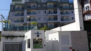 Un edificio moderno con entrada porticada, un letrero que indica un negocio o servicio, y un balcón con barandilla.