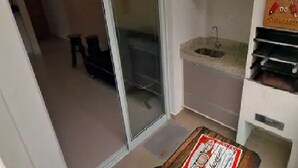 Una habitación pequeña con una puerta corrediza de vidrio que da a un balcón, un lavamanos y un mueble con un letrero encima.