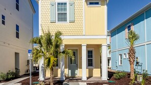 A two-story building with a yellow facade and a blue section on the right. There are palm trees in front of the building. - Relax & Reboot - Fantastic Margaritaville Cottage w/ Private Hot Tub (Kissimmee)