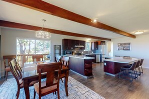 Una cocina amplia con vigas de madera, un comedor con una isla grande y vistas al exterior.
