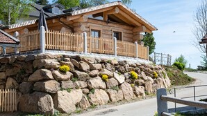 A wooden cabin with a stone foundation, a wooden fence, and a clear sky. - Ellerbeck Gesundheits- und Wellnesshof (Langdorf)