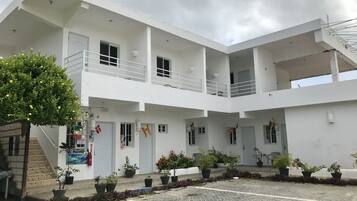 A modern building with multiple balconies, potted plants, and a paved courtyard.
