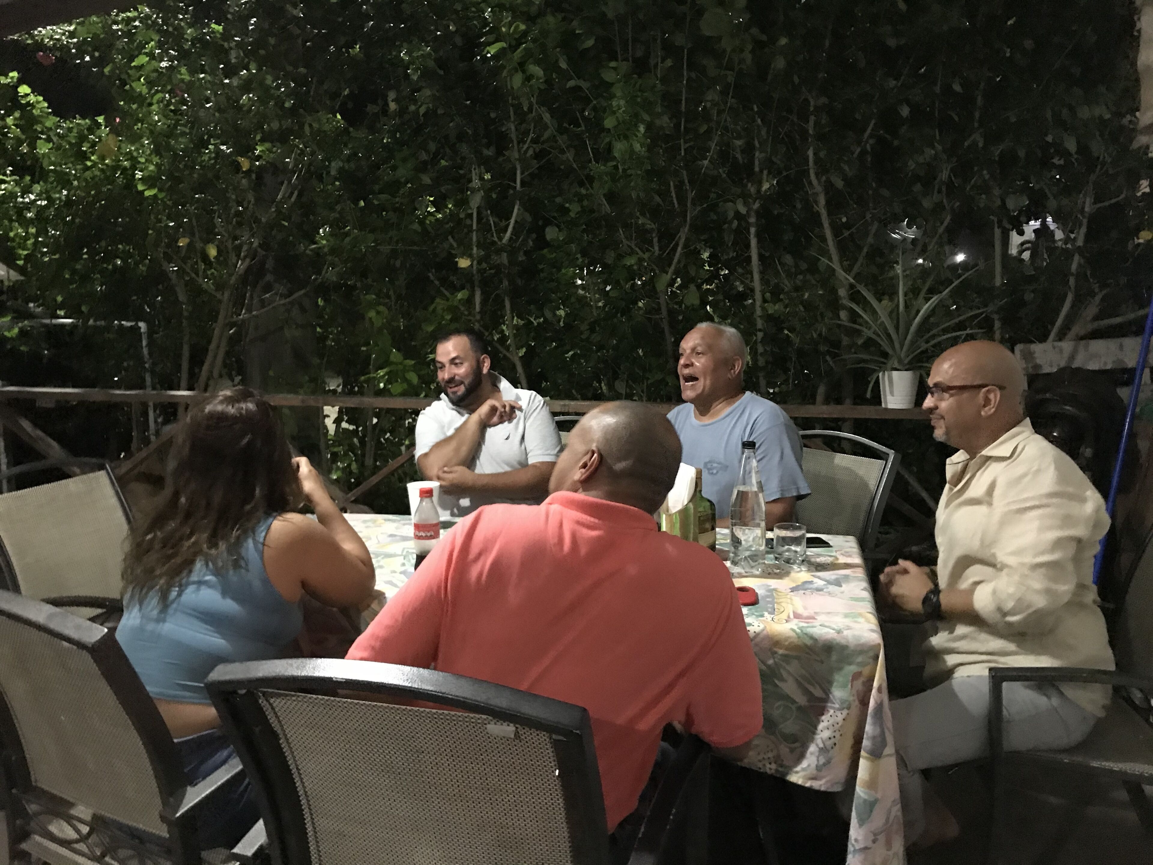 Un grupo de personas sentadas alrededor de una mesa al aire libre, posiblemente en un restaurante o café.