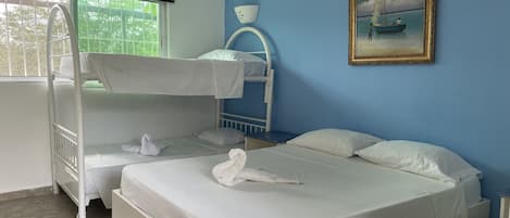A bunk bed room with white bedding and a painting of a boat on the wall.