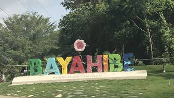 Une enseigne colorée sur laquelle sont écrits les mots « BAYAHIBE » et « PUEBLO ENCANTADO », le tout entouré de verdure.