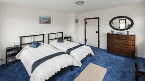 Ein Schlafzimmer mit zwei Einzelbetten, einem Schminktisch, einem Spiegel und einer Tür.