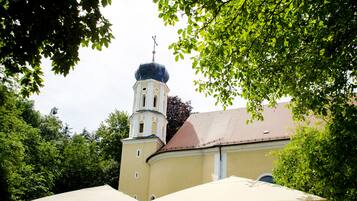 Uma igreja com uma torre de sino e uma cúpula, rodeada por árvores.