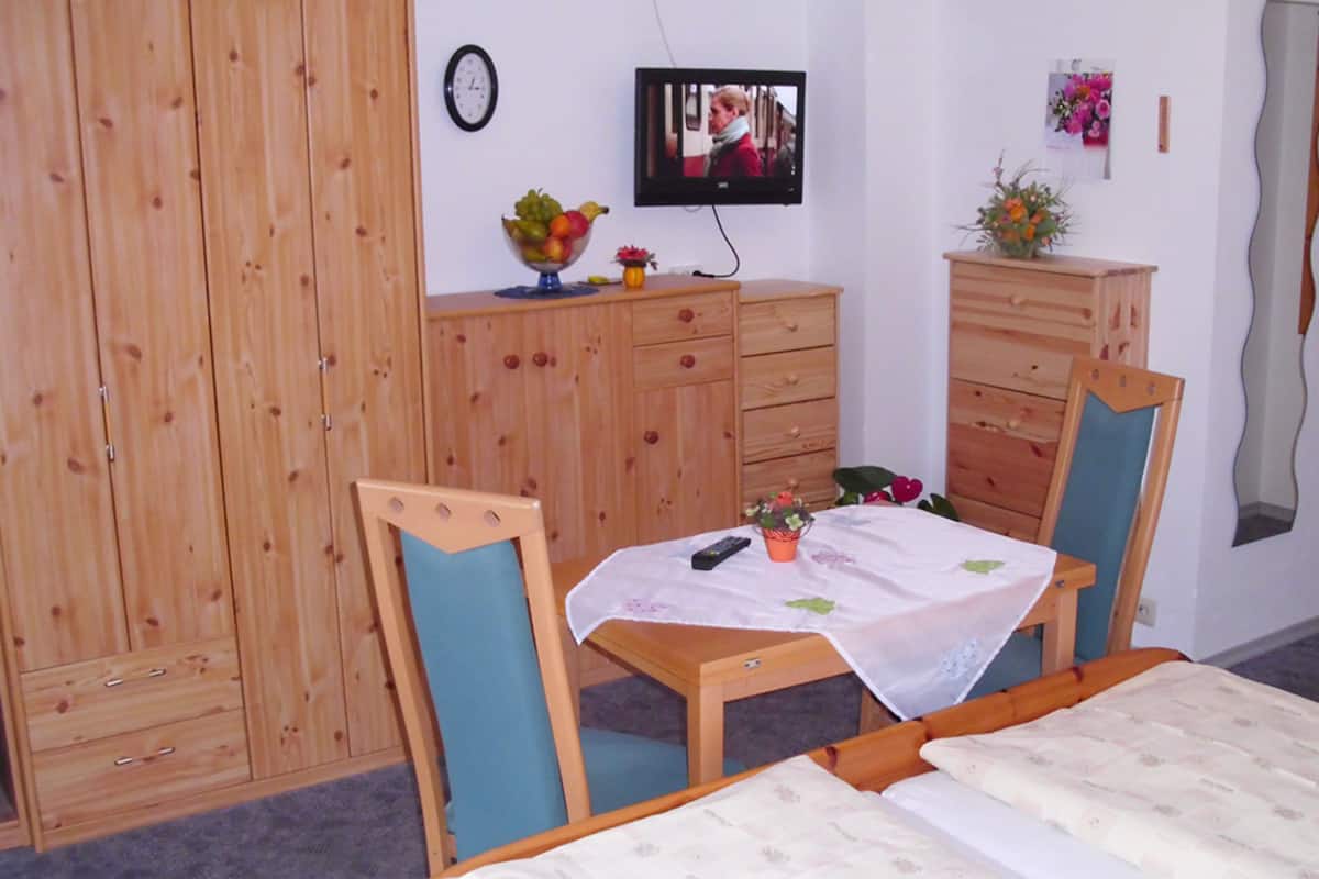Una habitación con cama, un escritorio de madera, televisión y armario.