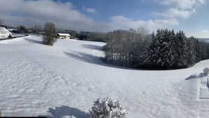 A snow-covered landscape with a pool area, houses, and trees. - Ferienwohnungen Martina (Windorf)