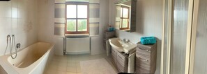 Une salle de bain avec une baignoire, un lavabo et une fenêtre.