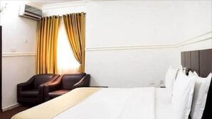 A hotel room with a bed, a desk, a chair, and a window with curtains. - Haitel Guest Inn (Kano)