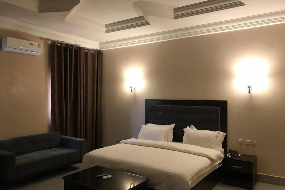 A hotel room with a bed, a sofa, a bedside table, and a nightstand.