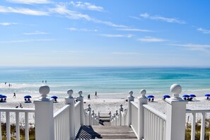 A beach with a wooden walkway leading to the shore, blue umbrellas, and white railings. - Great Outdoor Spaces And Short Walk To Seaside, FL Beach + 2 Adult Bikes! (Santa Rosa Beach)