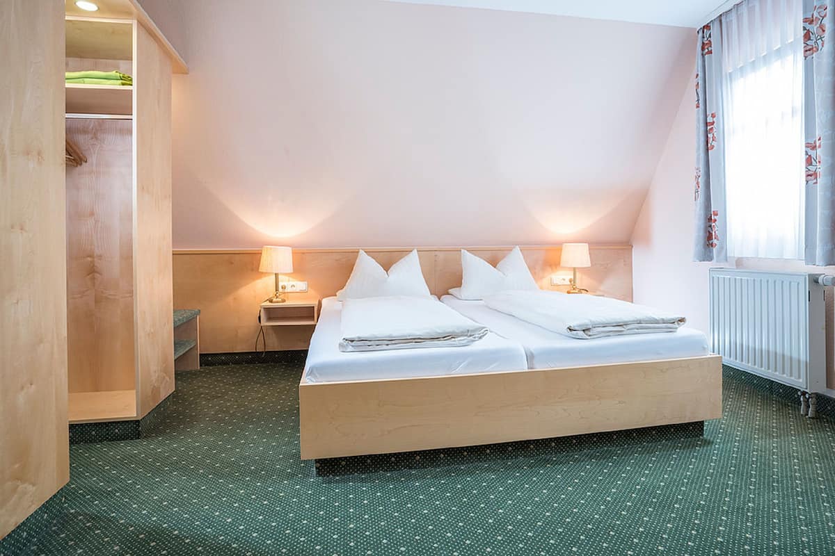 Een hotelkamer met een groot bed, twee nachtkastjes, een wandkast en een radiator.