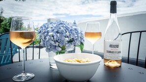 A table with two glasses of white wine, a bottle of wine, and a bowl of snacks. - Large Home in city center of Ponta Delgada: yard, near marina (great for groups) (Ponta Delgada)
