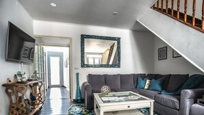Uma sala de estar com um sofá cinzento, uma mesa de centro e um tapete estampado.
